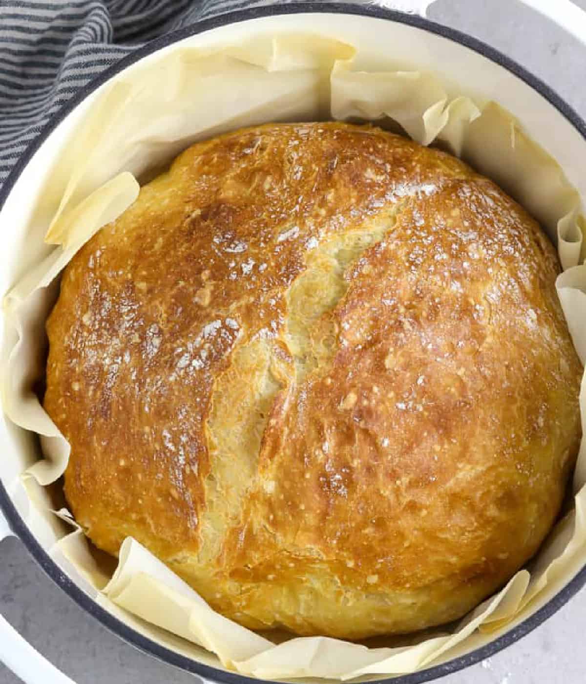 Fully baked artisan bread in a white pot for a roundup of vegan thanksgiving recipes. 