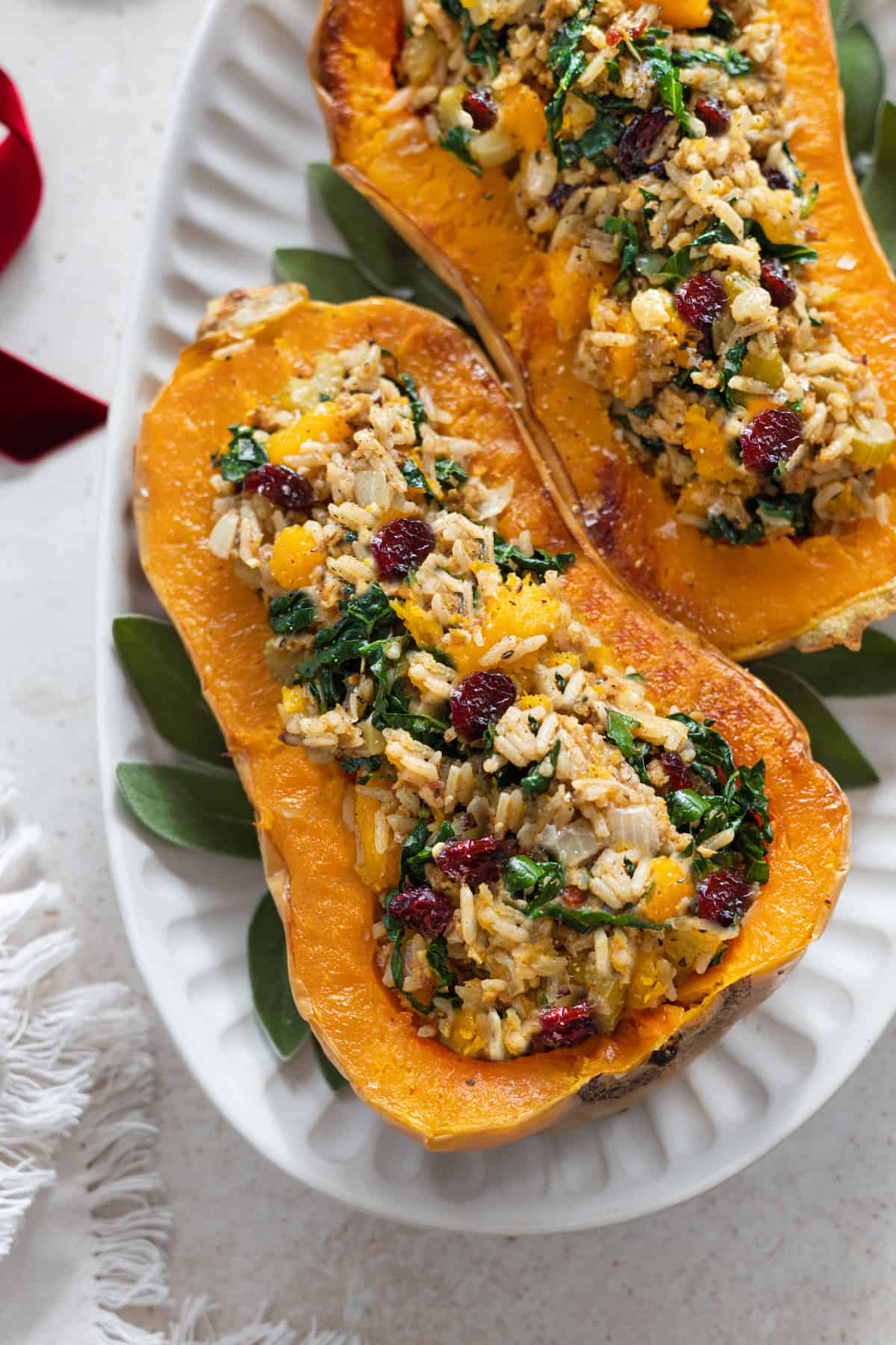 Two halves of stuffed butternut squash on a white serving platter. 