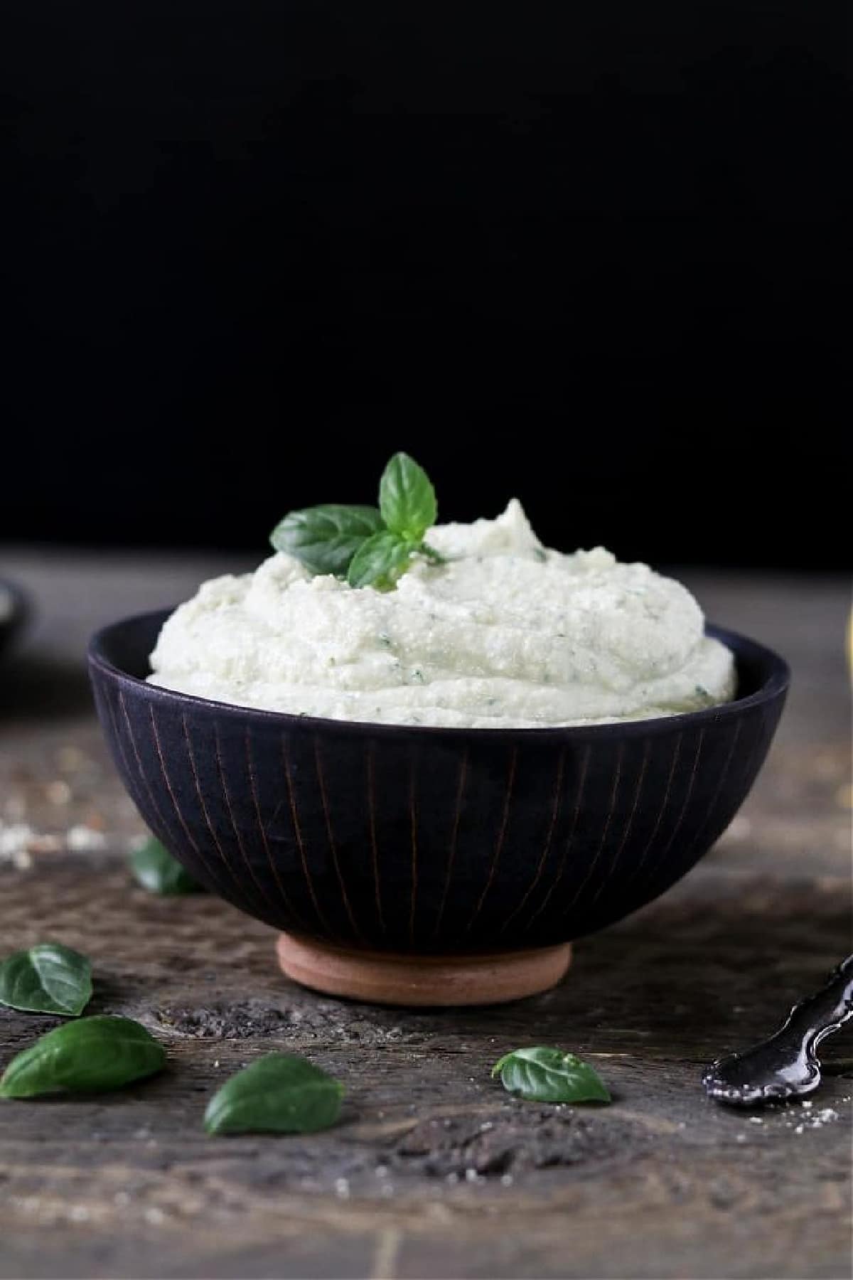 vegan ricotta cheese in a black bowl with basil on top. 