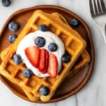overhead view of 2 waffles on a plate topped with berries.