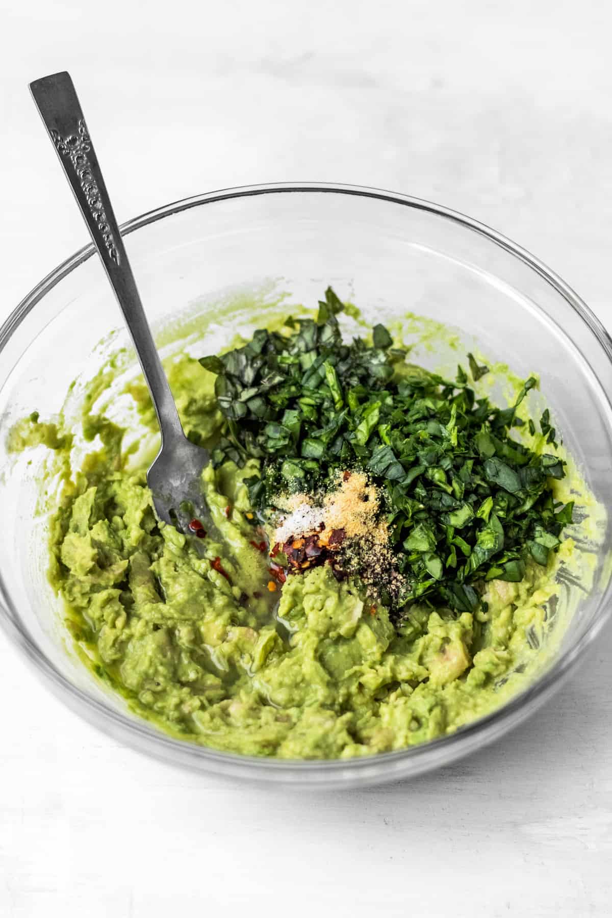 Adding fresh herbs and spices to the mashed beans and avocado. 