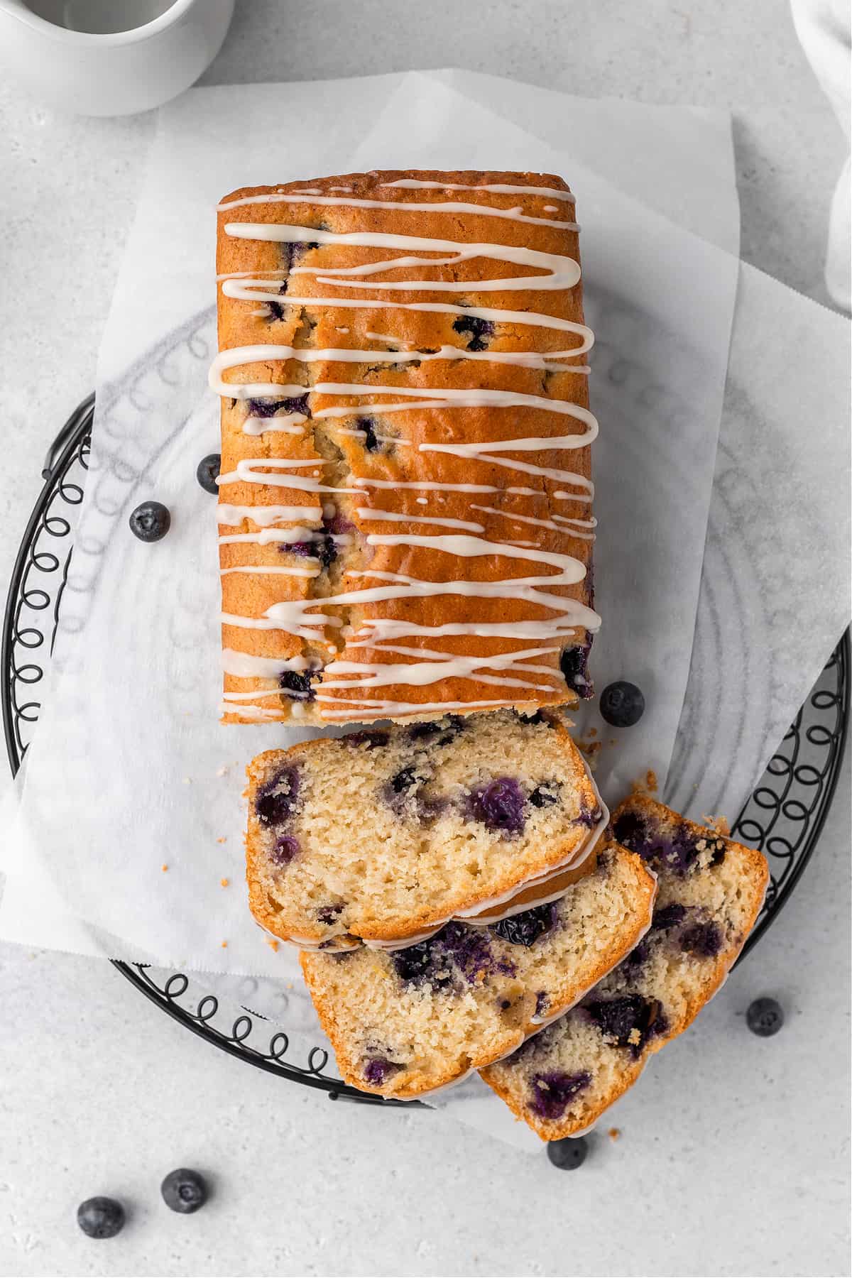 Overhead view of partially sliced lemon blueberry bread on a cooling rack.