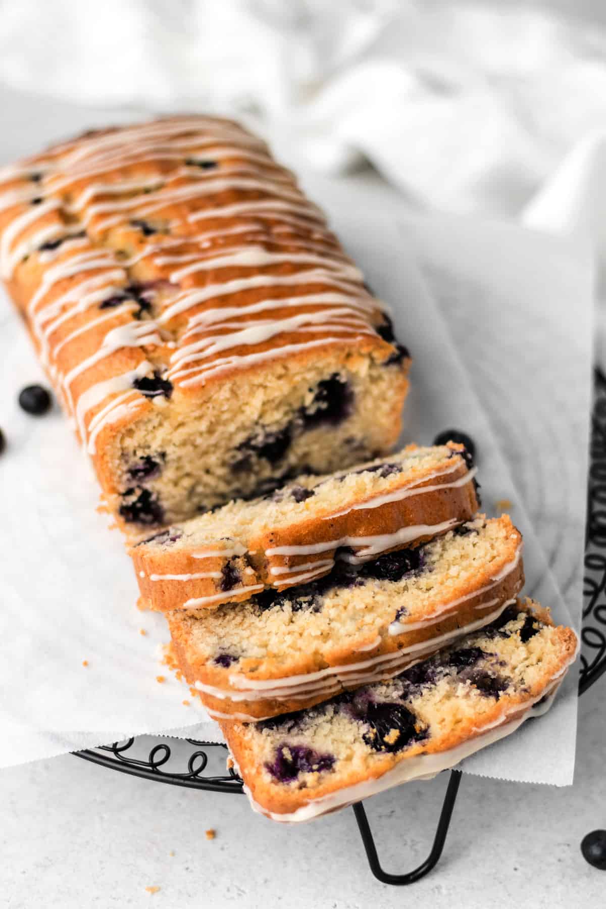 Fully baked lemon blueberry bread cut into slices on parchment paper. 