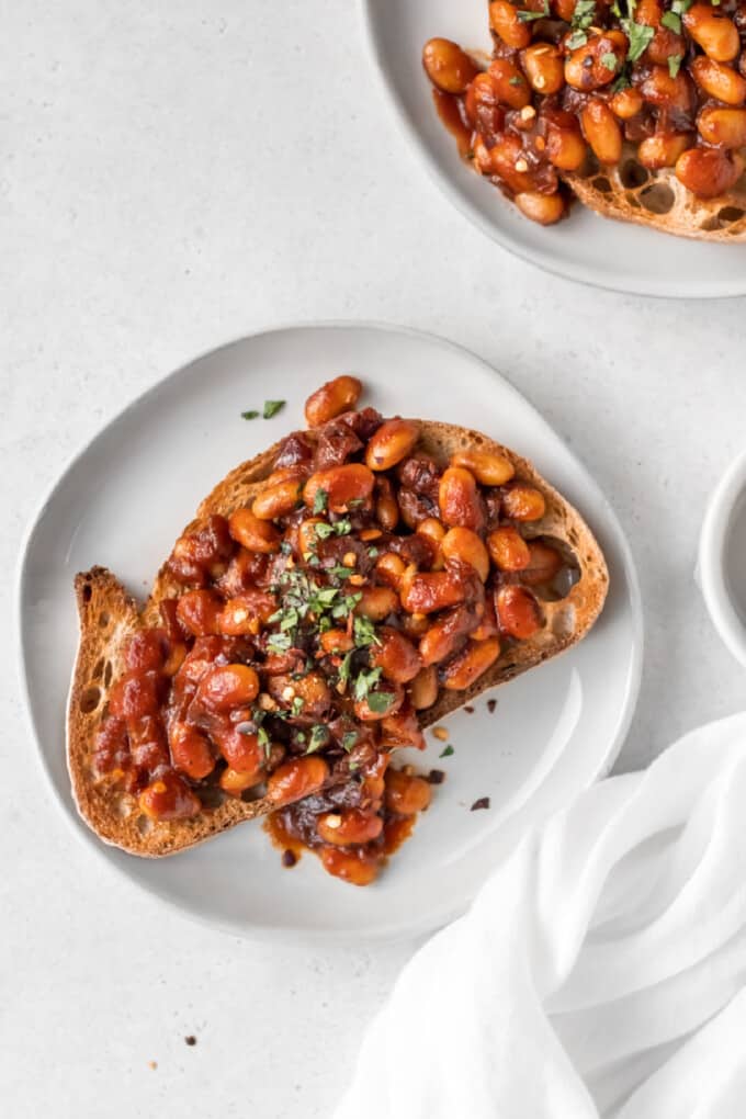 Overhead view displaying two pieces of toast topped with beans on a white plate.