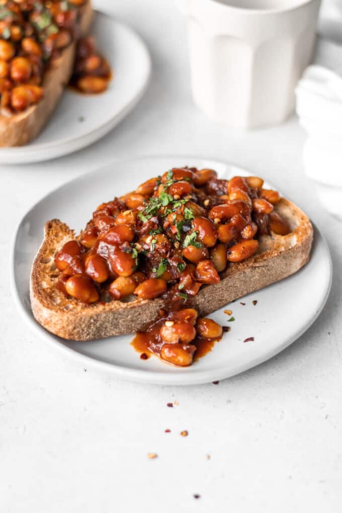 Two pieces of toast topped with beans on a white plate.