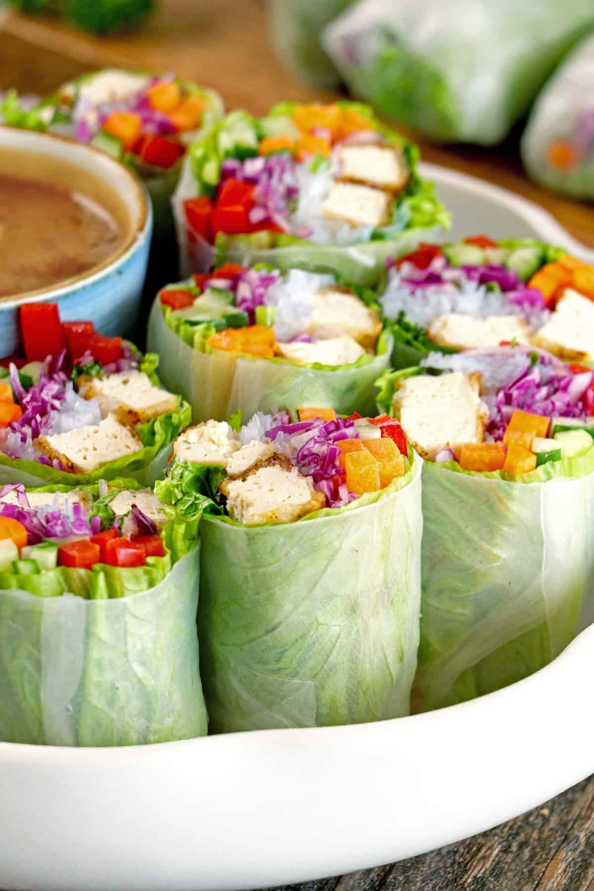 Closeup view of fresh spring rolls on a white serving tray. 