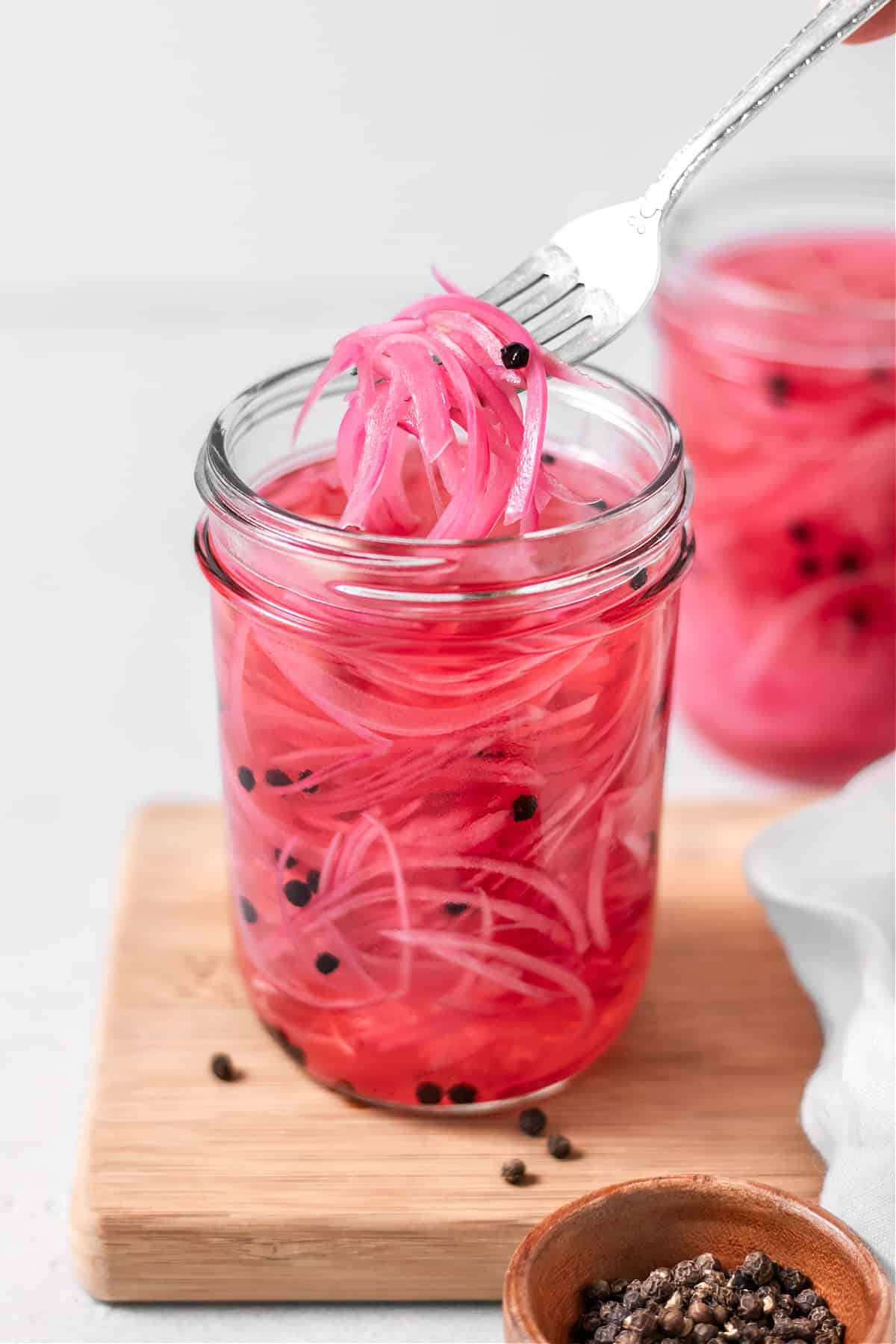 Two jars of quick pickled red onions on a cutting board. 