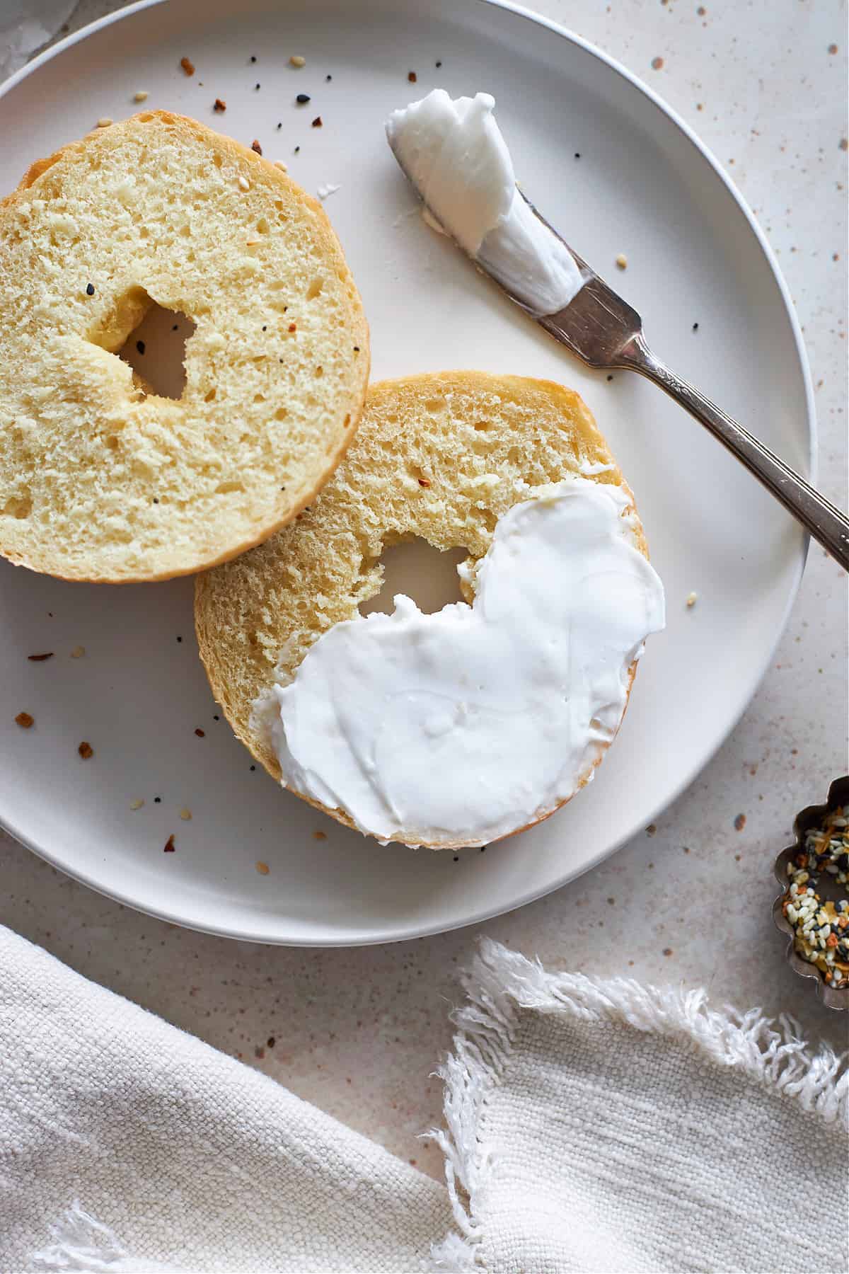 Overhead view of a vegan bagel cut in half with cream cheese on top.