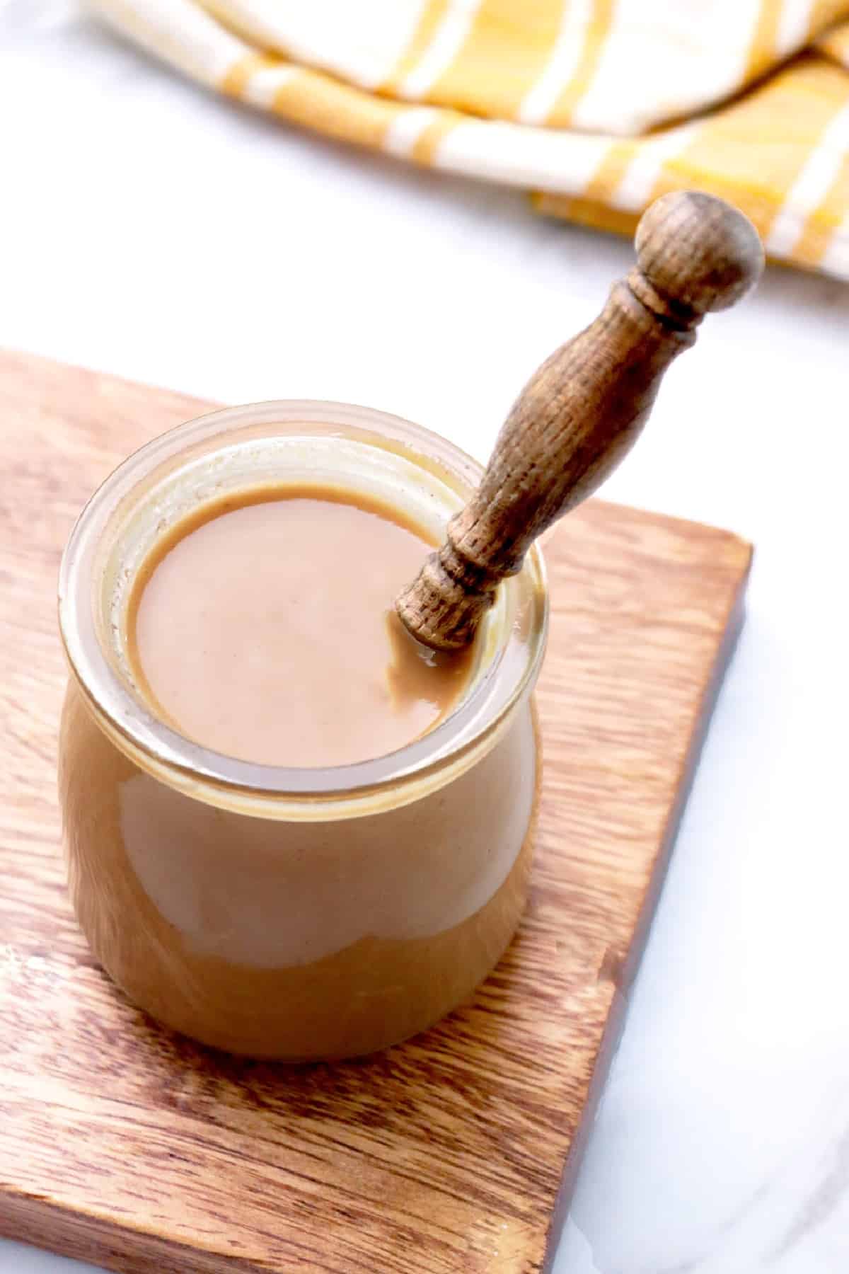 Overhead view of peanut sauce in a jar with a linen napkin in the background.