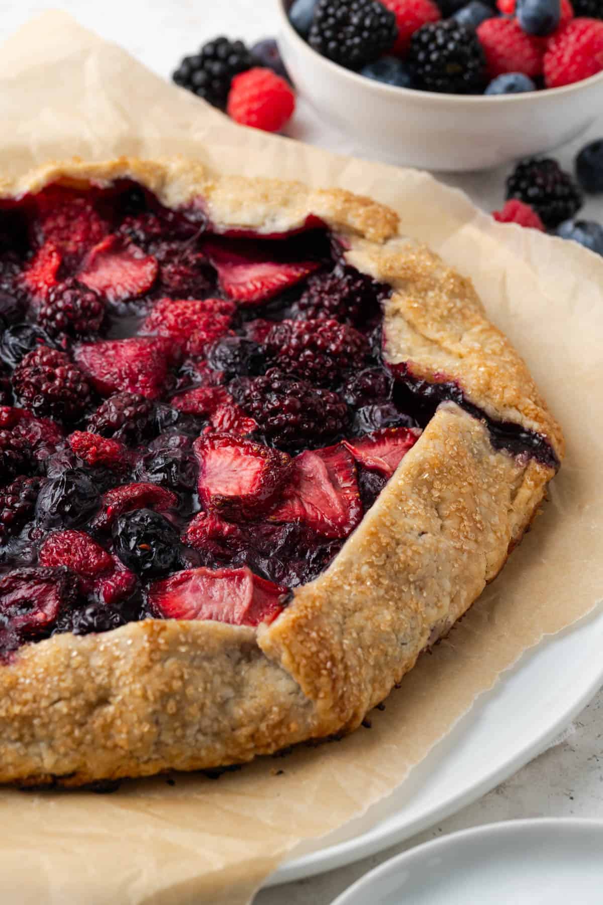 Side view of a fully baked berry galette on top of parchment paper. 