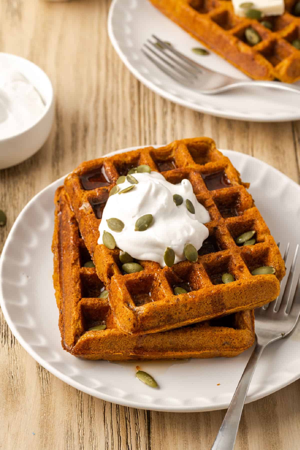 vegan pumpkin waffles on a plate with a fork on the side. 