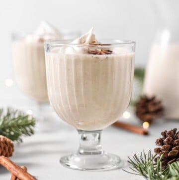 vegan eggnog in a glass with whipped cream on top.