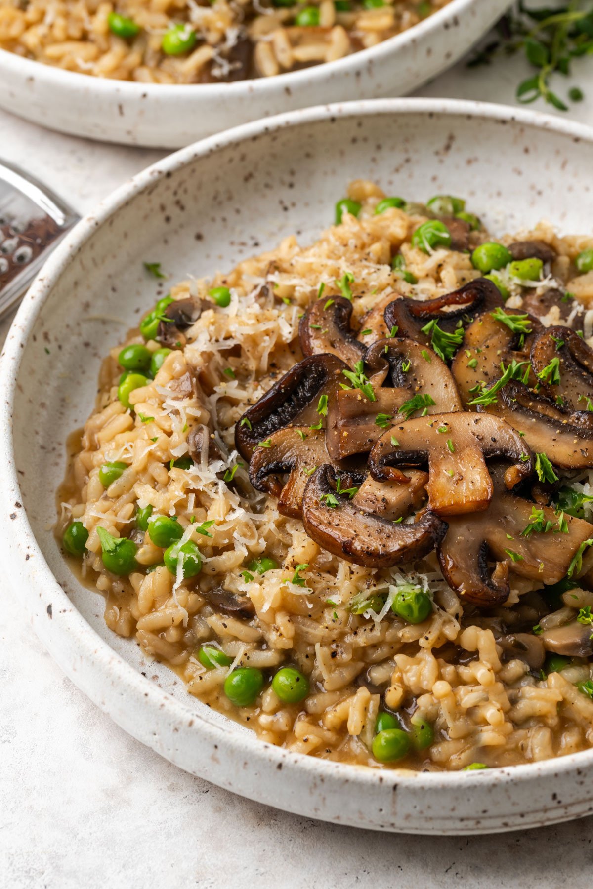 close up view of mushroom risotto in a bowl with sauteed mushrooms on top. 