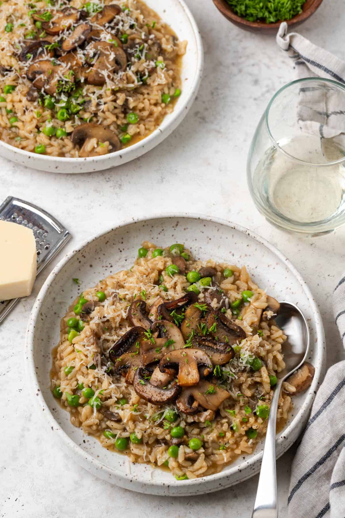 Two bowls of Instant Pot Mushroom Risotto with cheese and parsley on the side. 