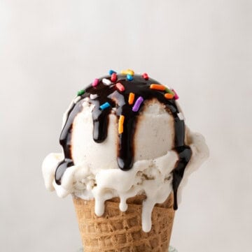vegan vanilla ice cream cone with chocolate sauce on top.