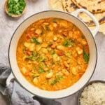 butter bean curry in a pot with rice and naan on the side.