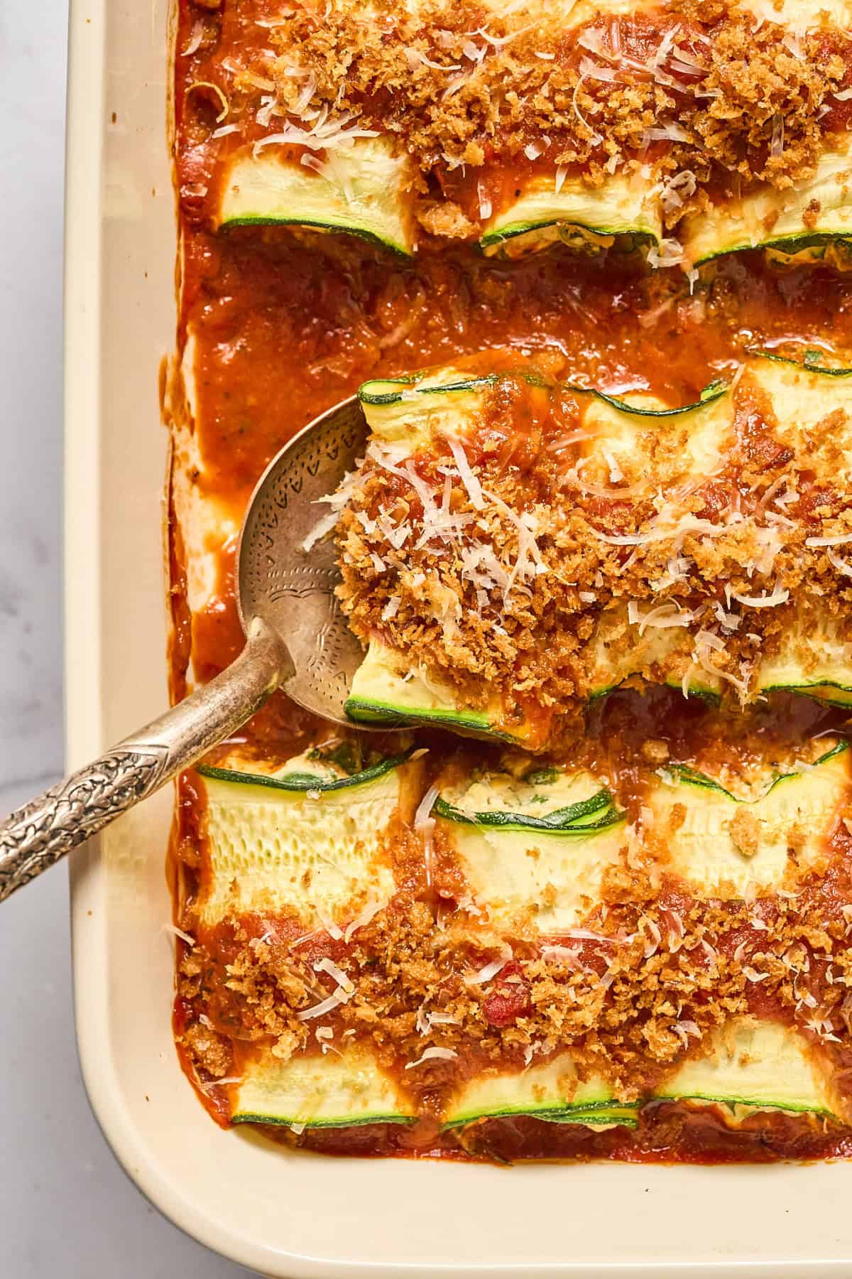 Close up view of freshly baked vegan zucchini rollatini in a casserole dish.