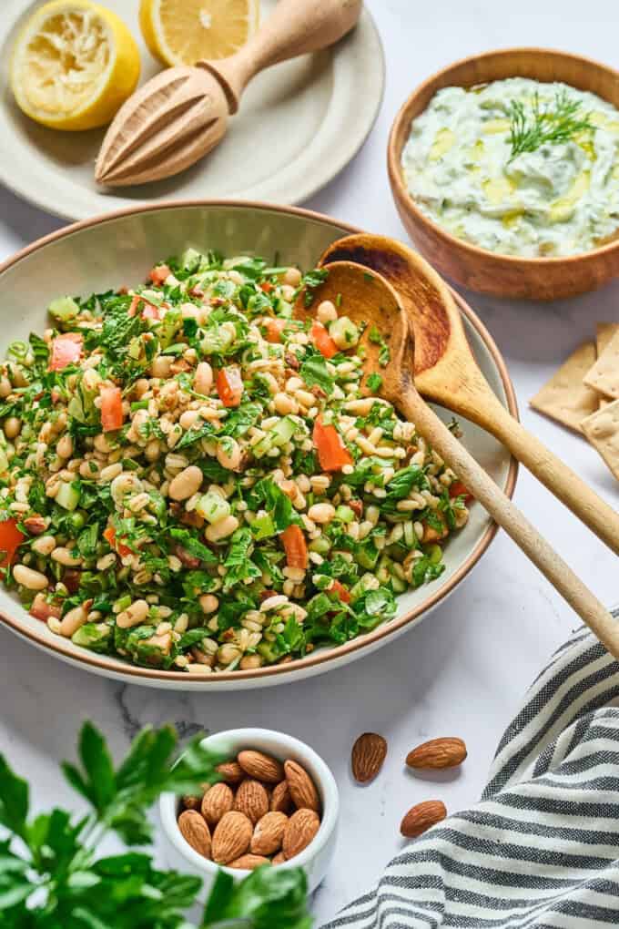 Salad displayed in a bowl with serving spoons on side.