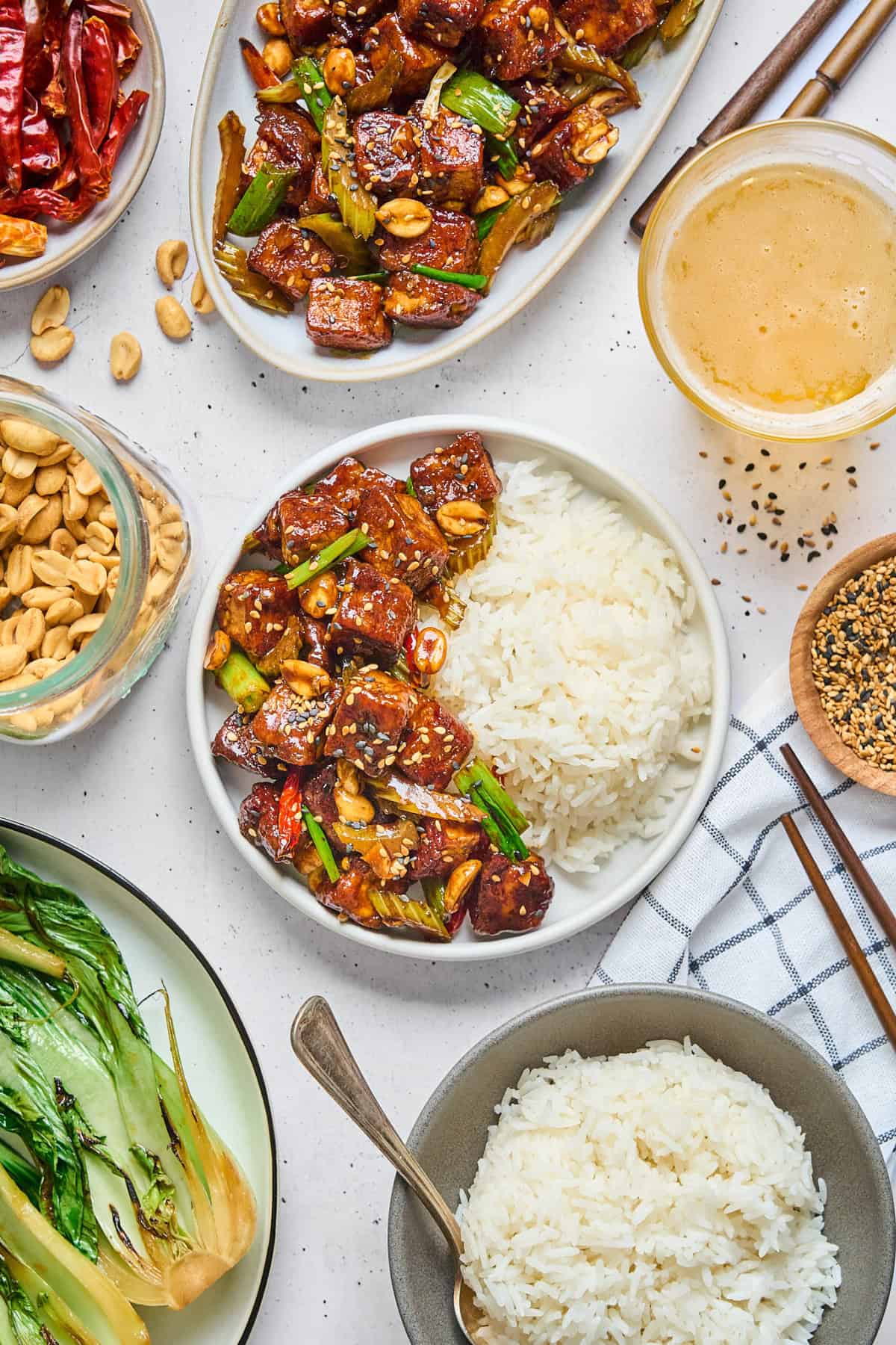 Overhead view of kung pao tofu on a plate with a side of rice and bok choy on the side.