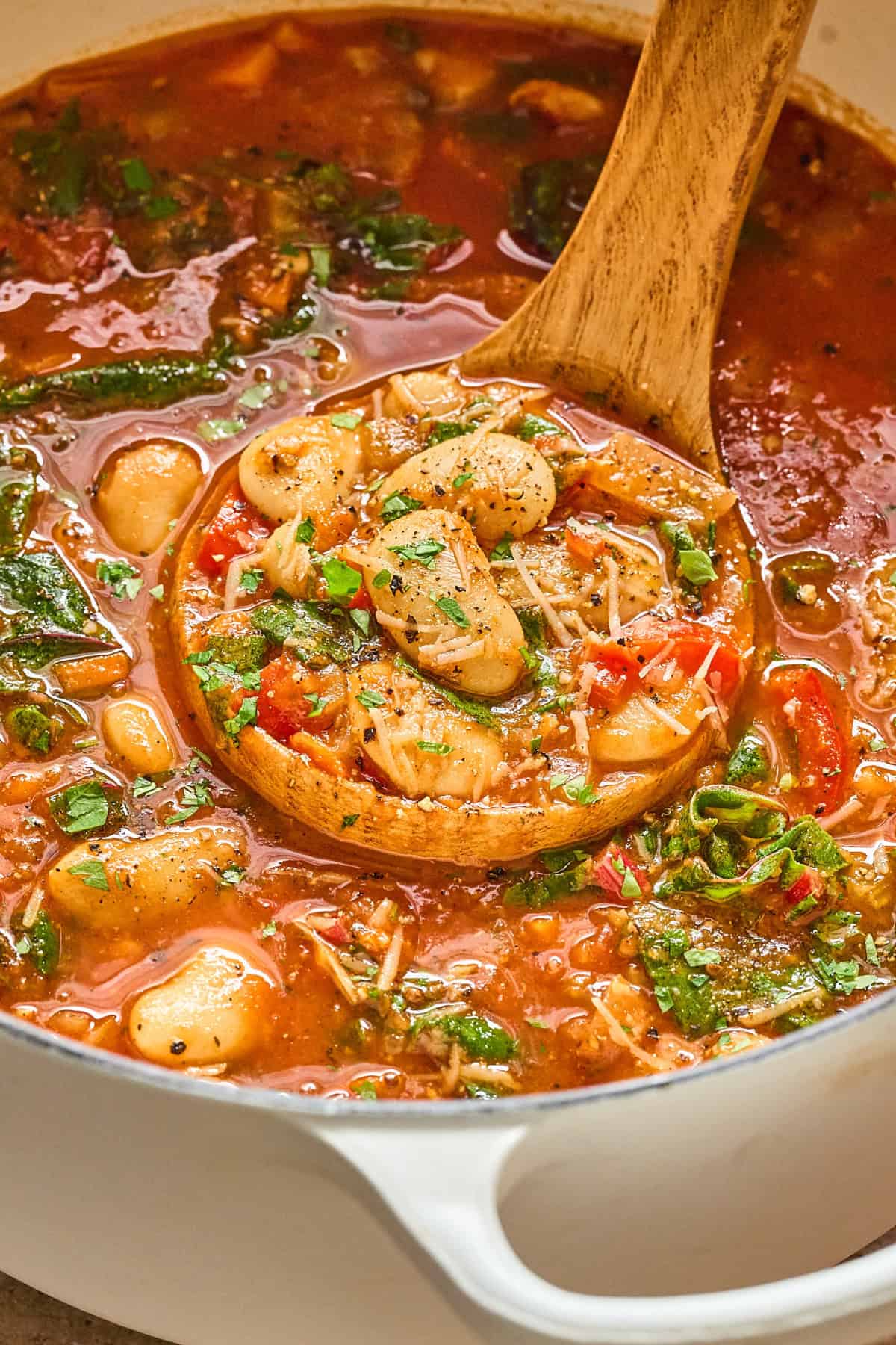 Up close view of a pot of butter bean stew with a ladle inside.