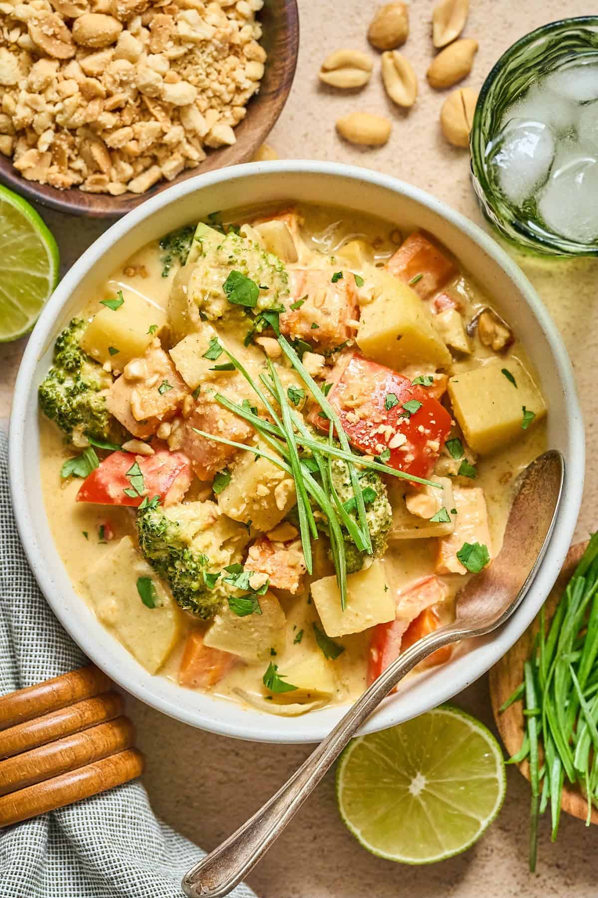 vegan Thai yellow curry in a white bowl with peanuts and lime on the side. 
