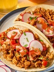 two fully assembled shredded tofu tacos on a plate.