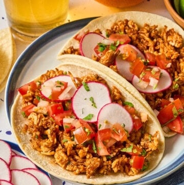 two fully assembled shredded tofu tacos on a plate.