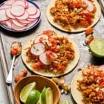 three fully assembled shredded tofu tacos on a sheet pan.