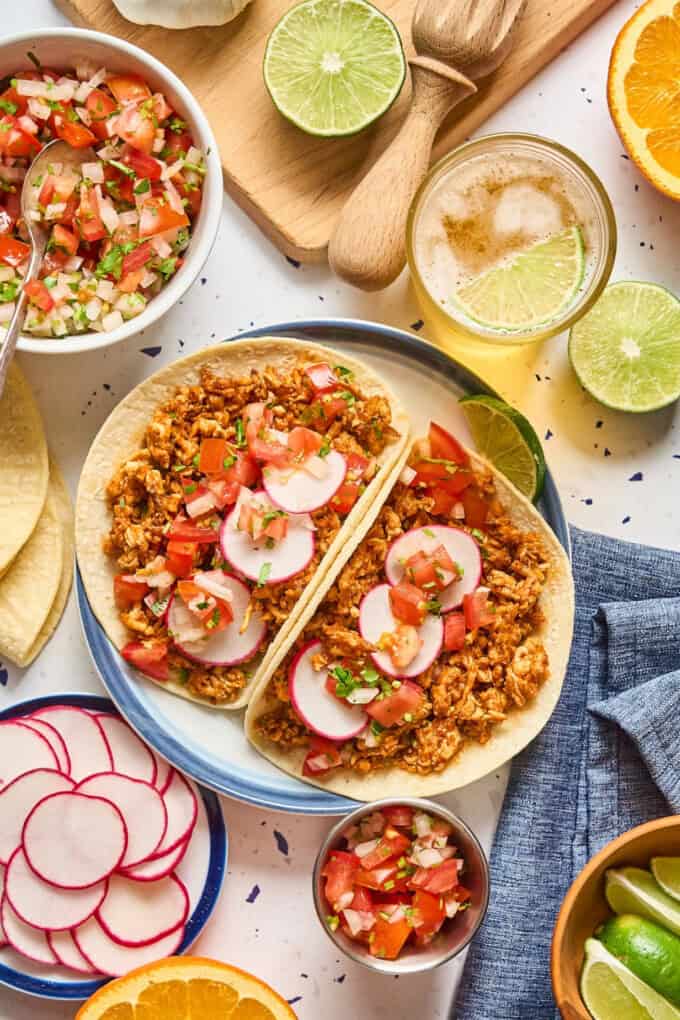 two tacos on a plate with toppings on the side.