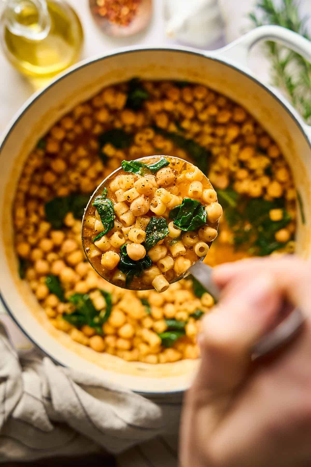 Overhead view of pasta e ceci on a ladle with a pot underneath.