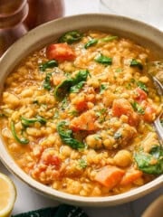 a bowl of red lentil stew in a white bowl with a spoon inside.
