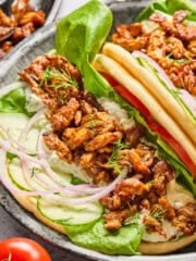 two vegan gyros on a plates with yogurt sauce in the background.