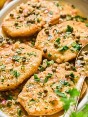 fully prepared tofu piccata on a serving plate with a spoon on the side.