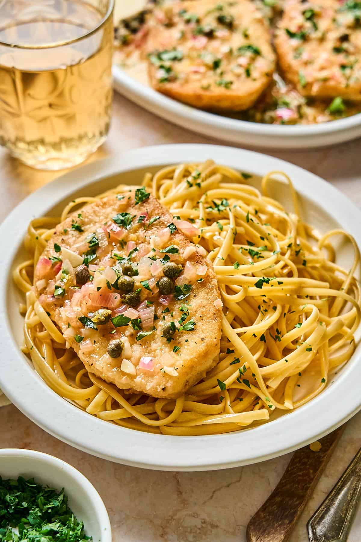 One piece of tofu piccata on a plate with pasta on the side. 