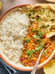 overhead view of vegan dal makhani in a bowl with naan inside.