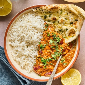 overhead view of vegan dal makhani in a bowl with naan inside.