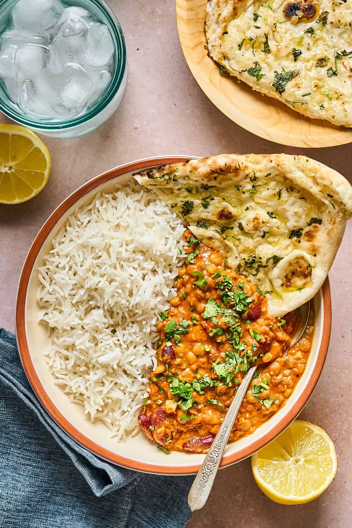 overhead view of a bowl of Vegan Dal Makhani  with rice and naan. 