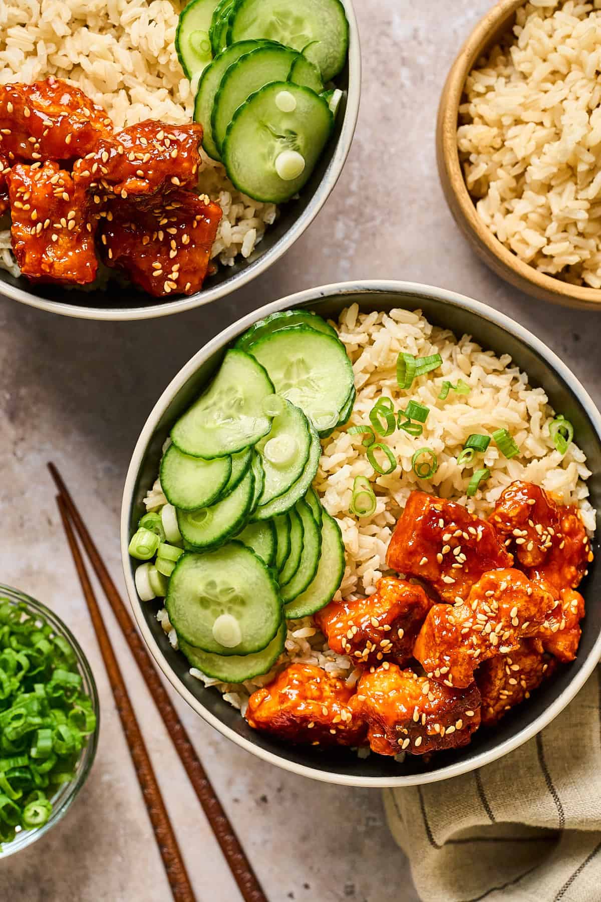 overhead view of two bowls of gochujang tofu with rice and cucumber. 