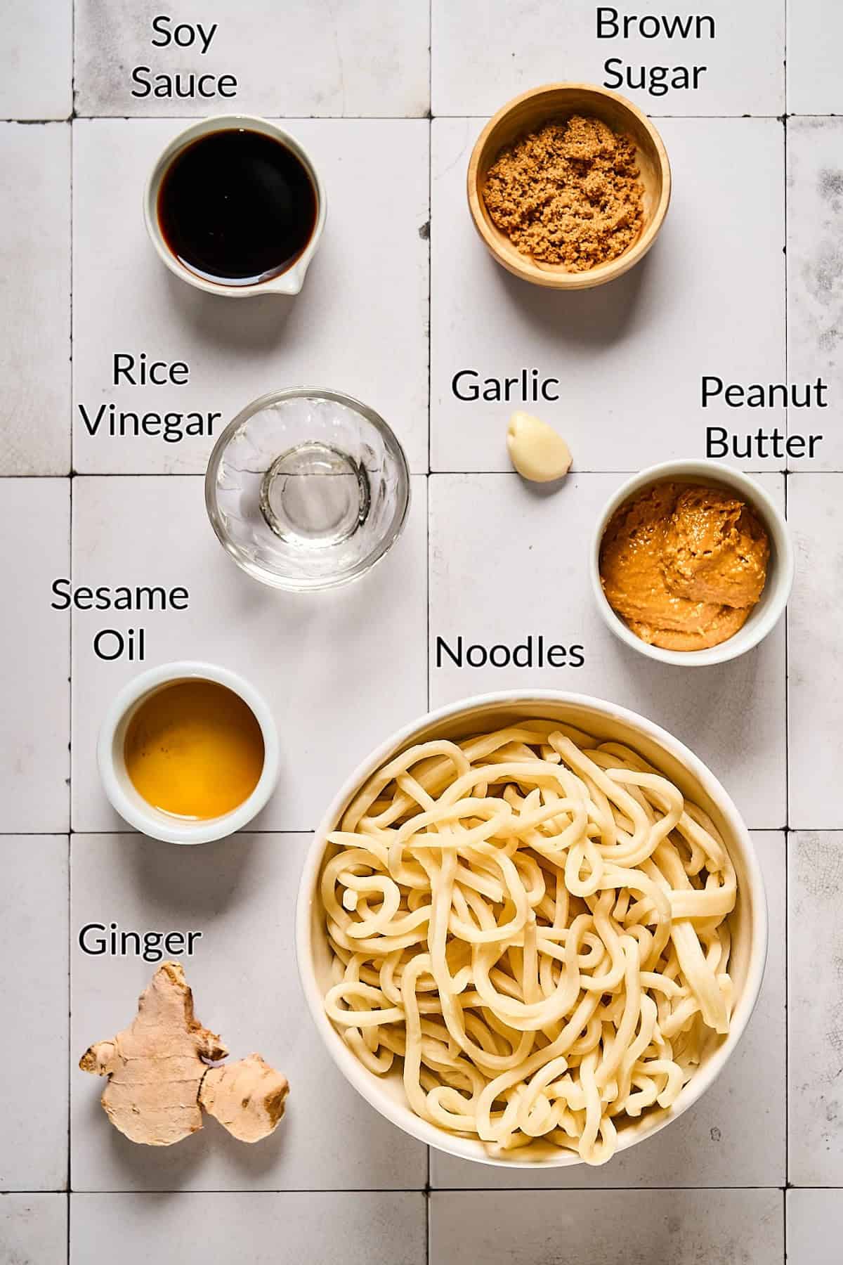 ingredients to make noodle dish on a tiled table top. 