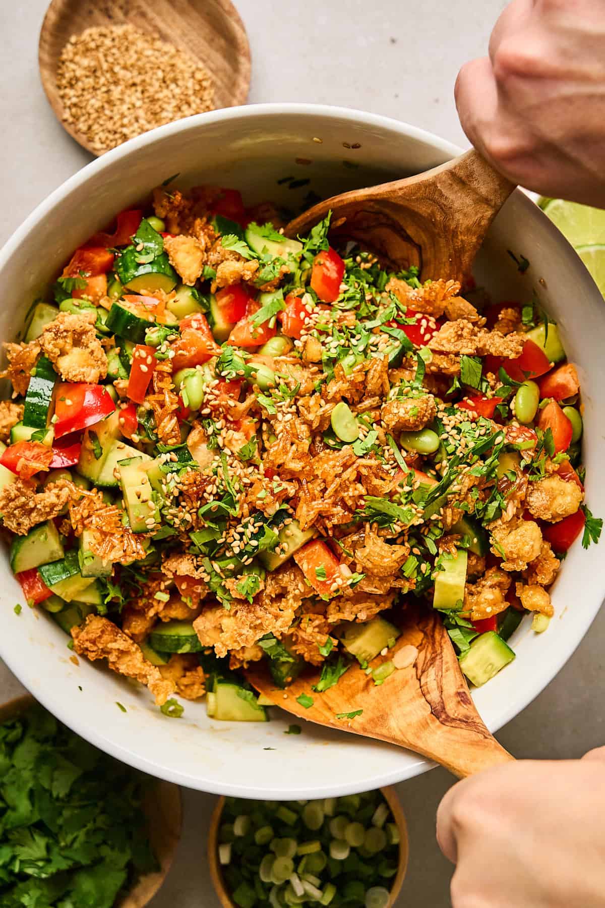 Overhead view of crispy rice salad in a bowl with wood serving utensils on the side. 