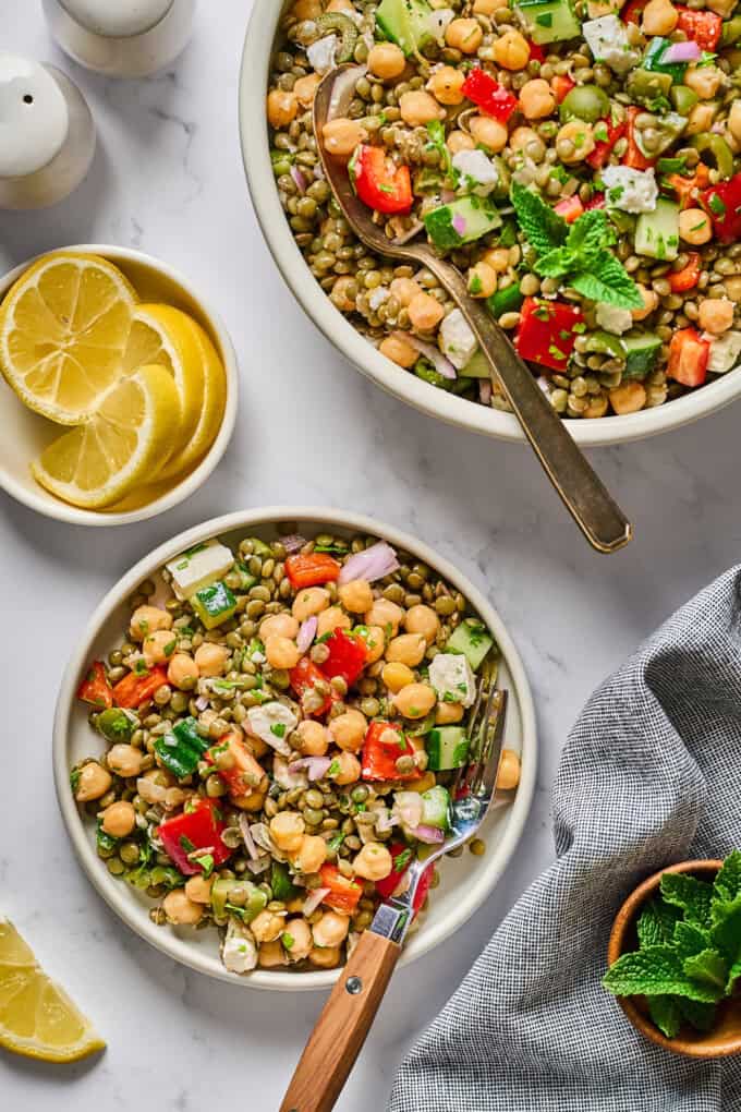 overhead view of two bowls filled with salad with lemon on the side.