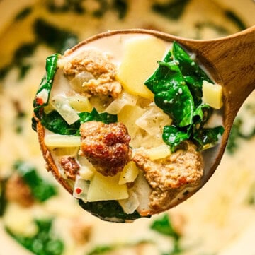 Vegan Zuppa Toscana with kale, potatoes, and plant-based sausage in a spoon.